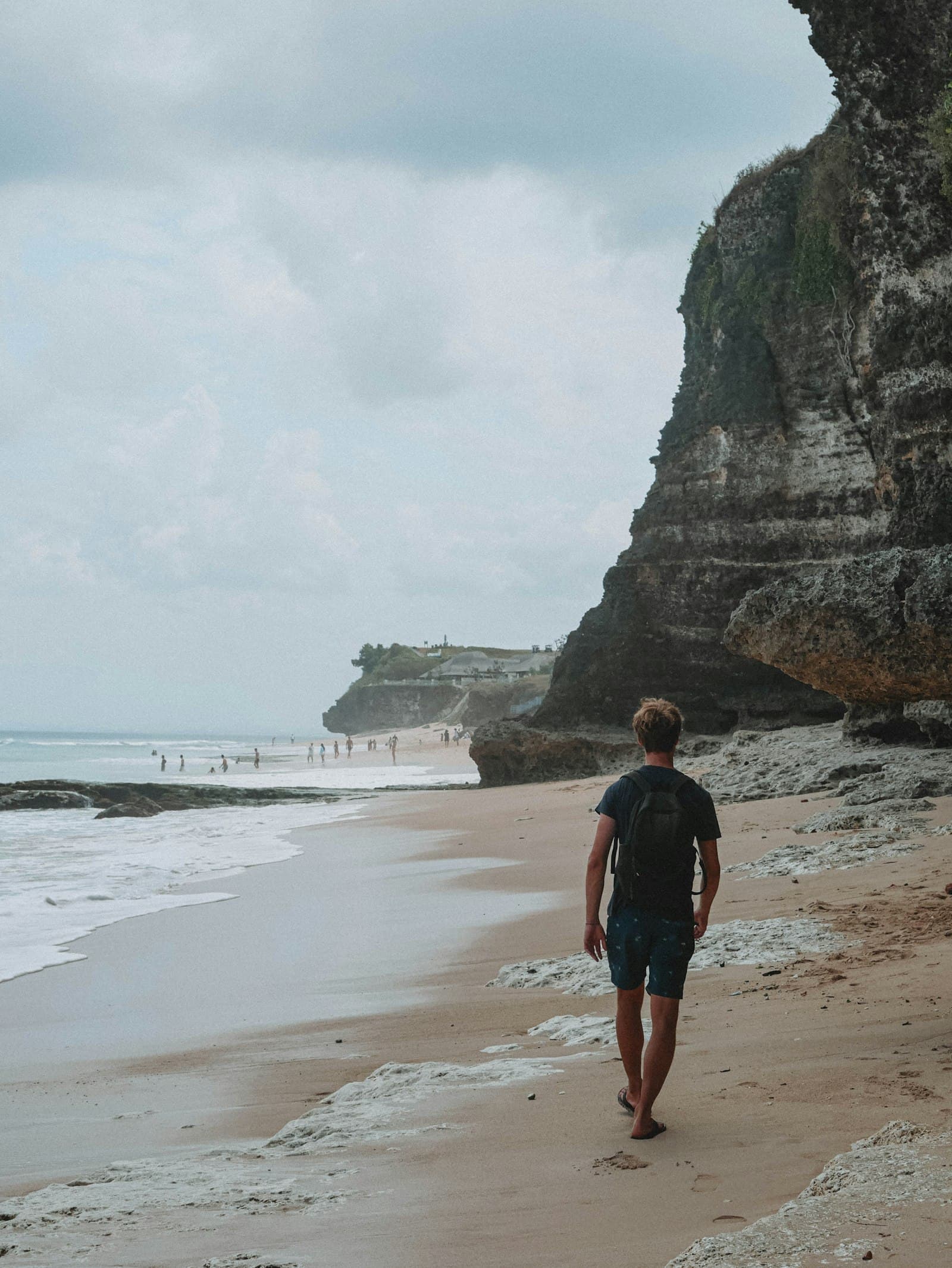 Man walking along a quiet beach beside the ocean