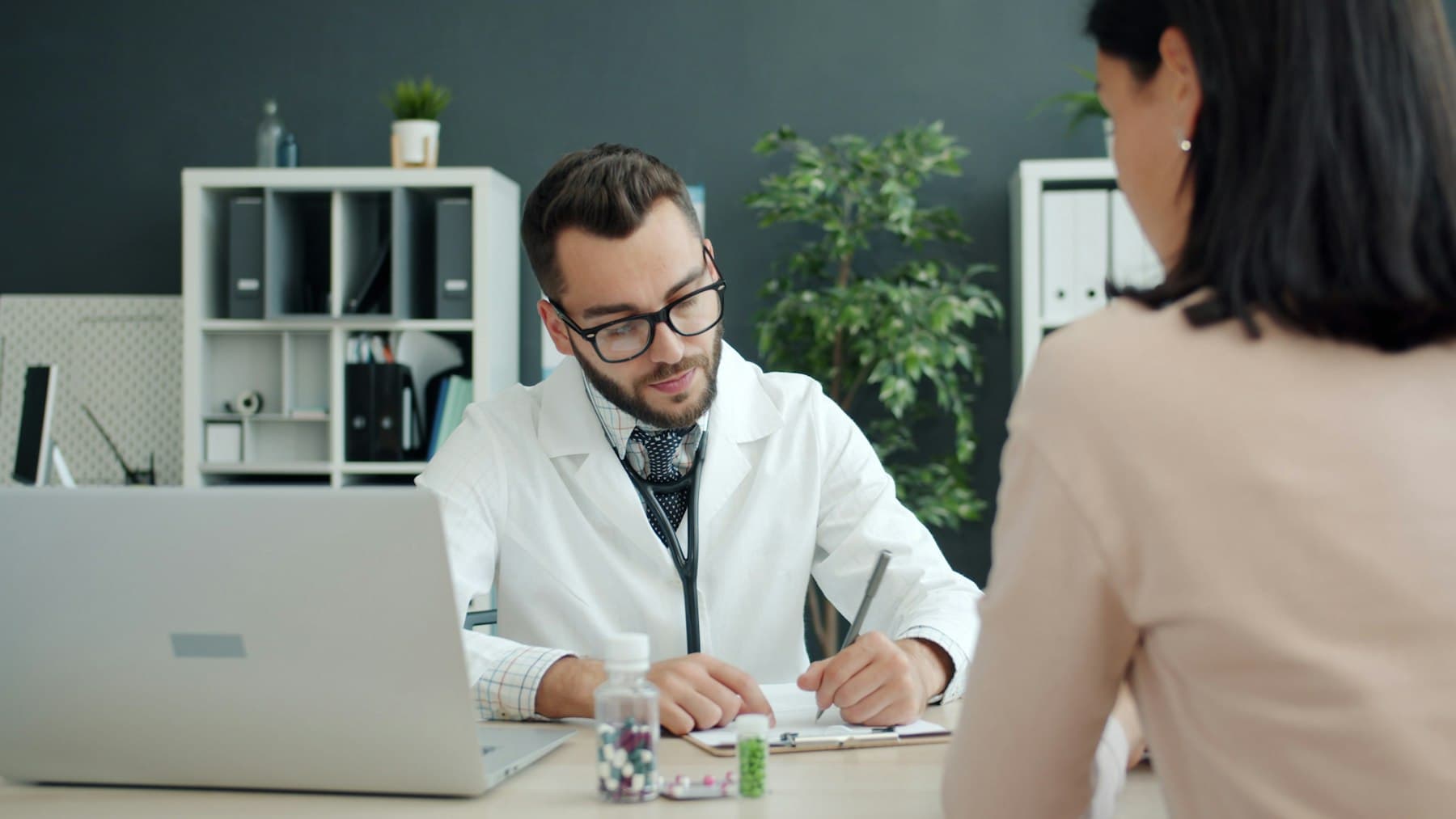 Clinician writing notes while speaking with a patient
