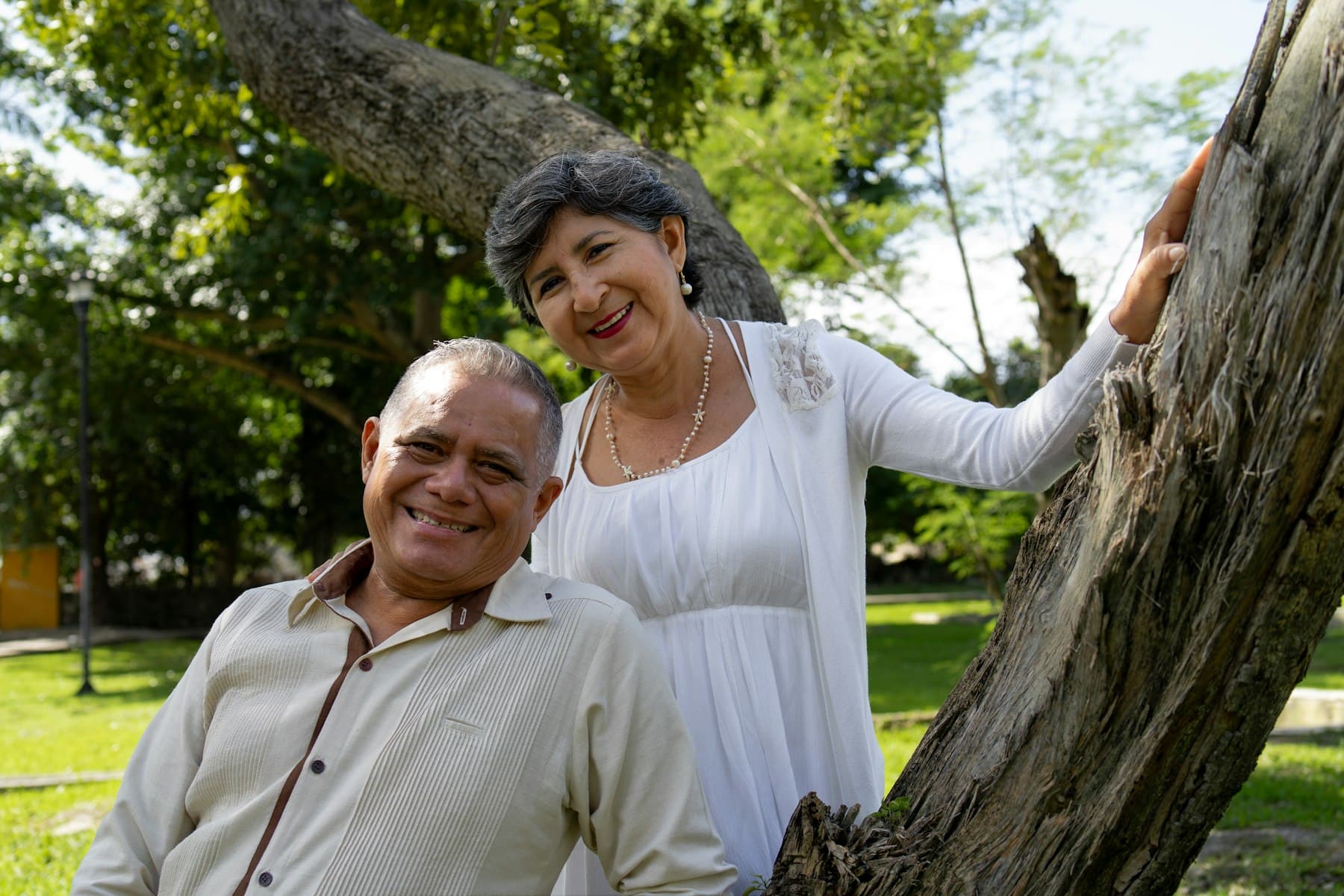 Smiling couple standing together near a tree outdoors