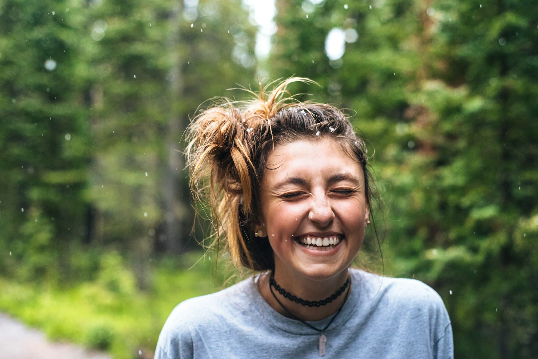 Woman smiling while standing near a tree outdoors