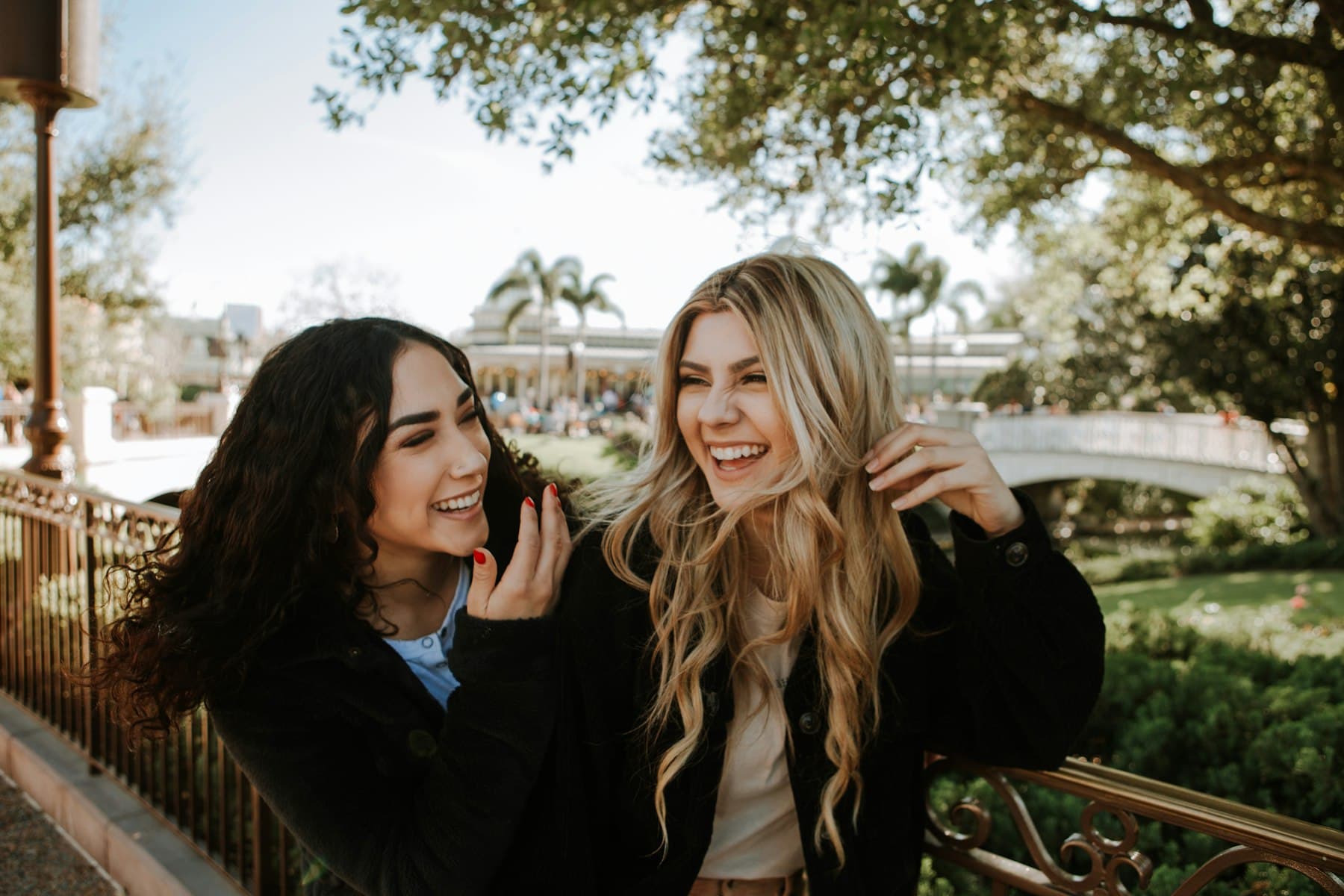 Two women smiling while standing near trees